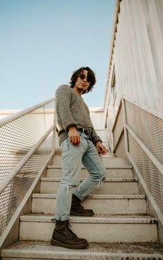 a man standing on some stairs with his hands in his pockets