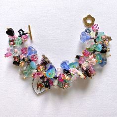 a multicolored necklace with lots of beads and charms hanging from it's side