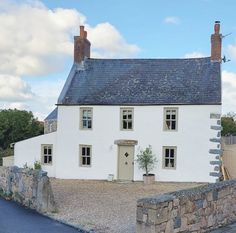 a white house sitting next to a stone wall