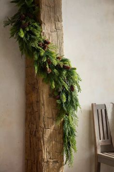 a piece of wood that has some pine cones and evergreen leaves on it next to a chair