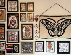 the wall is covered with many framed pictures and art work, including a butterfly - shaped crochet piece