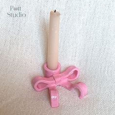 a pink candle is sitting on top of a white tablecloth with the word pot studio written below it