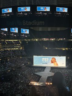 a large screen in the middle of a stadium filled with people