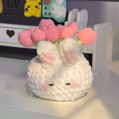 a white crocheted vase with pink flowers in it on top of a table