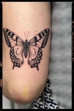 a black and white butterfly tattoo on the side of a woman's leg,