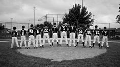 a group of baseball players standing next to each other in front of a ball field