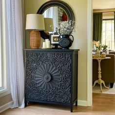 a living room with a mirror, lamp and table in it's centerpiece