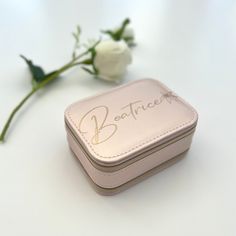 a small pink box with writing on it next to a flower