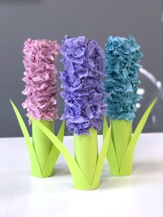 three vases with paper flowers in them sitting on a table