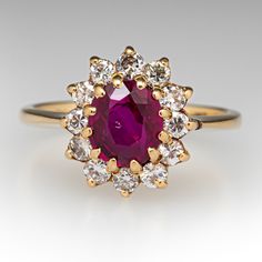 an oval shaped ruby and diamond ring with yellow gold accents, on a white background