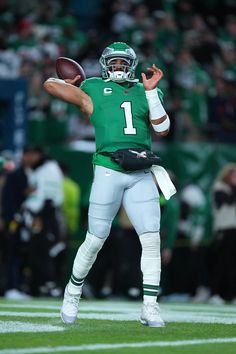 a football player throwing a ball on top of a field with people in the background