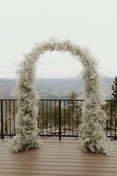 A oval wedding arch completely covered with babies breath flowers sits on a wooden deck with the mountains in the background. Babies Breath Arch, Wedding Aisle Decorations Outdoor, Baby's Breath Wedding Flowers, Sage Green Wedding Colors, White Wedding Arch, Floral Arch Wedding, Provence Wedding, Dream Wedding Decorations, Cottage Wedding