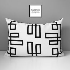 a black and white pillow sitting on top of a table next to a gray wall