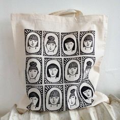 a tote bag with black and white images of women's heads on it