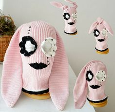 a pink knitted sweater with black and white flowers on the front, along with matching mittens and booties