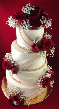 a three tiered wedding cake with red roses and baby's breath