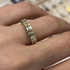 a woman's hand holding a ring with three baguets on it,