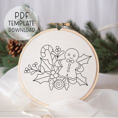 a cross stitch christmas ornament on a white background with pine cones and evergreen branches