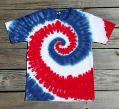 a red, white and blue tie - dyed t - shirt sitting on top of a wooden floor