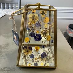 a glass box with flowers painted on it sitting on a table next to a chair