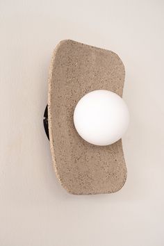 an egg sitting on top of a piece of concrete next to a wall light fixture