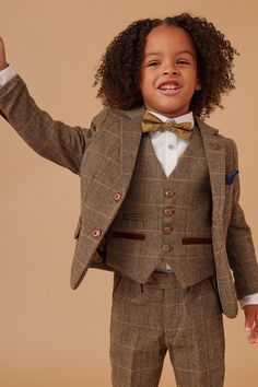 This heritage children's three-piece makes the perfect statement on the wedding day. Crafted with vintage inspired wool-mix cloth, it adopts a herringbone weave in earthy tones and works beautifully for country barn weddings. The multi-tonal check is synonymous with 19th century tweeds yet the colour pop accents give it that modern edge. Model wears size 5 yrs. Features Herringbone Single-breasted Notch lapel Single back vent Three button cuff Double button blazer fastening Complimentary pocket square Decorative waistcoat adjuster strap Adjustable waistband Matching adults suit Style tip Pair with a white shirt and knitted tie in rust Composition 65% Polyester 23% Viscose 12% Wool Fall Wedding Tweed Jacket, Wool Tweed Jacket For Fall Wedding, Fall Wedding Wool Tweed Jacket, Fitted Brown Tweed Three-piece Suit, Classic Brown Sets For Fall, Vintage Wedding Suits For Fall, Grandad Collar Shirt, Country Barn Weddings