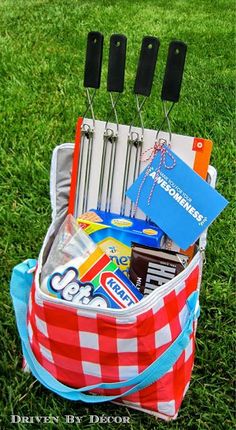 a red and white checkered bag with utensils in it on the grass