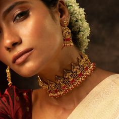 Description : This statement silver choker set from our Mandira collection showcases the Goddess Lakshmi motif inside a temple structure. Highlighted with semi-precious coral stones and cluster pearl drops, this handcrafted choker set is perfect for wedding celebrations, parties, or special events. Product Information : Materials used: 925 Silver with Antique Yellow Gold Plating Stones: Semi-precious stones & semi-precious beads Findings: Hook and links Fusion Kundan Necklace For Wedding And Navratri, Diwali Celebration Temple Necklace Choker, Diwali Celebration Temple Choker Necklace, Festive Temple Jewelry Choker For Wedding, Festive Temple Choker Necklace For Celebration, Elegant Choker With Latkans For Festive Occasions, Festive Temple Jewelry Wedding Choker, Elegant Festive Choker With Latkans, Festive Celebration Temple Choker Necklace