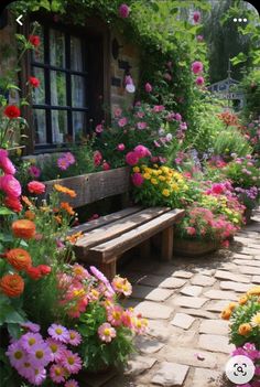 a garden filled with lots of flowers next to a wooden bench on a brick walkway