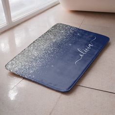 a blue bath mat with the name julia written on it in silver glitters next to a white tub