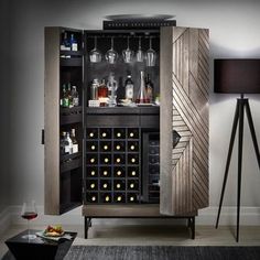 a cabinet with wine glasses and bottles in it next to a lamp on a table