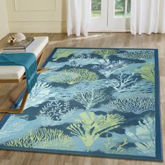 a blue rug with green and yellow corals on it in front of a window