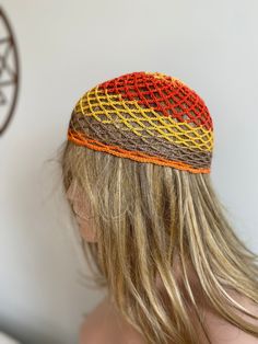 a woman with long blonde hair wearing a multicolored knitted hat