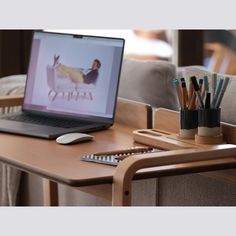 an open laptop computer sitting on top of a wooden desk next to a cup of pencils