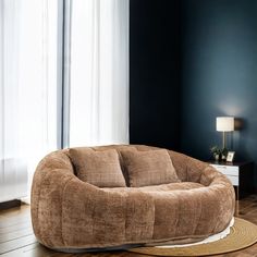 a brown bean bag chair sitting on top of a wooden floor next to a window