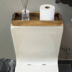 a white toilet sitting in a bathroom next to a wooden holder with two rolls of toilet paper on it