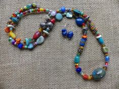 This 35 inch necklace is made from many different types of beads in many colors.  The main focal bead is a large blue gray ceramic bead with brown running through.  There are African trade beads, African Christmas beads, coral, glass, jasper, agate, shell, and many more.  It has a small hook and eye clasp.  This is a very versatile strand.  The earrings are included in the set.  This long necklace with receive tons of compliments! African Christmas, Christmas Beads, Heishi Necklace, Nugget Necklace, Black Onyx Necklace, African Trade Beads, Ethnic Necklaces, Trade Beads, Agate Necklace