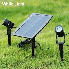 three solar powered lights in the grass with one light on it's side and another on its back