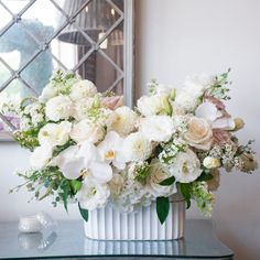 a vase filled with white and pink flowers on top of a table next to a mirror