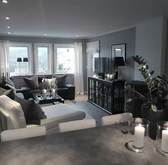 a living room filled with lots of furniture next to tall windows and candles on the table