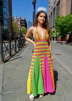 a woman standing on the sidewalk wearing a colorful dress