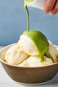 a bowl filled with ice cream covered in green sauce and being drizzled over it