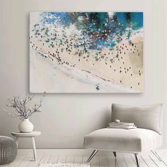 a painting hanging on the wall above a chair and ottoman in a room with white walls