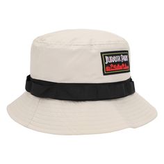 Step into the world of Jurassic Park fashion with this striking white bucket hat. A black band wraps around, setting the stage for the woven label that proudly displays the iconic movie title against a backdrop of vibrant red jungle foliage. But this hat isn't just about style – it's designed with functionality in mind. The fleece-lined side pocket adds a practical touch, making it easy to carry your essentials while embracing the adventurous spirit of the franchise. Crafted from high-quality po White Retro Adjustable Bucket Hat, Retro White Adjustable Bucket Hat, White Flat Brim Bucket Hat For Outdoor, White Adjustable Retro Bucket Hat, Vintage Bucket Hat With Flat Brim For Outdoor, Retro Adjustable Bucket Hat With Flat Brim, Vintage Flat Brim Bucket Hat For Outdoor, Urban Bucket Hat With Adjustable Short Brim, White Bucket Hat With Letter Print