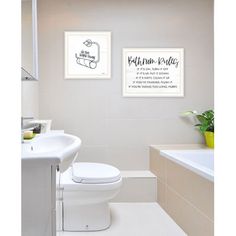 a white toilet sitting next to a bath tub under a framed poster on the wall