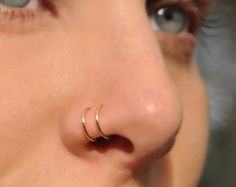 a close up of a person with two piercings on their nose and one behind her ear