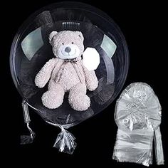 a teddy bear in a clear plastic container next to an organ bag with a bow on it