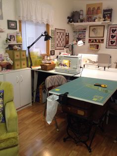 a sewing machine sitting on top of a wooden floor next to a green chair and table