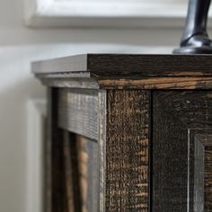 a wooden cabinet with a faucet on top of it and a window in the background