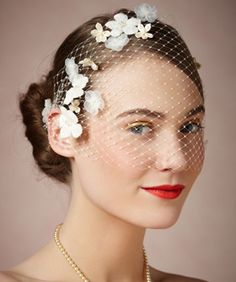 a woman wearing a veil with flowers on it and pearls in her hair is posing for the camera